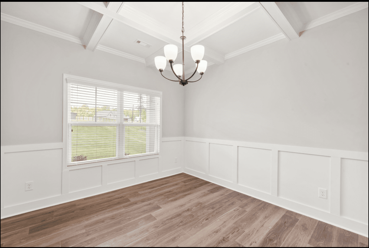 Bright dining room with chandelier and wainscoting.