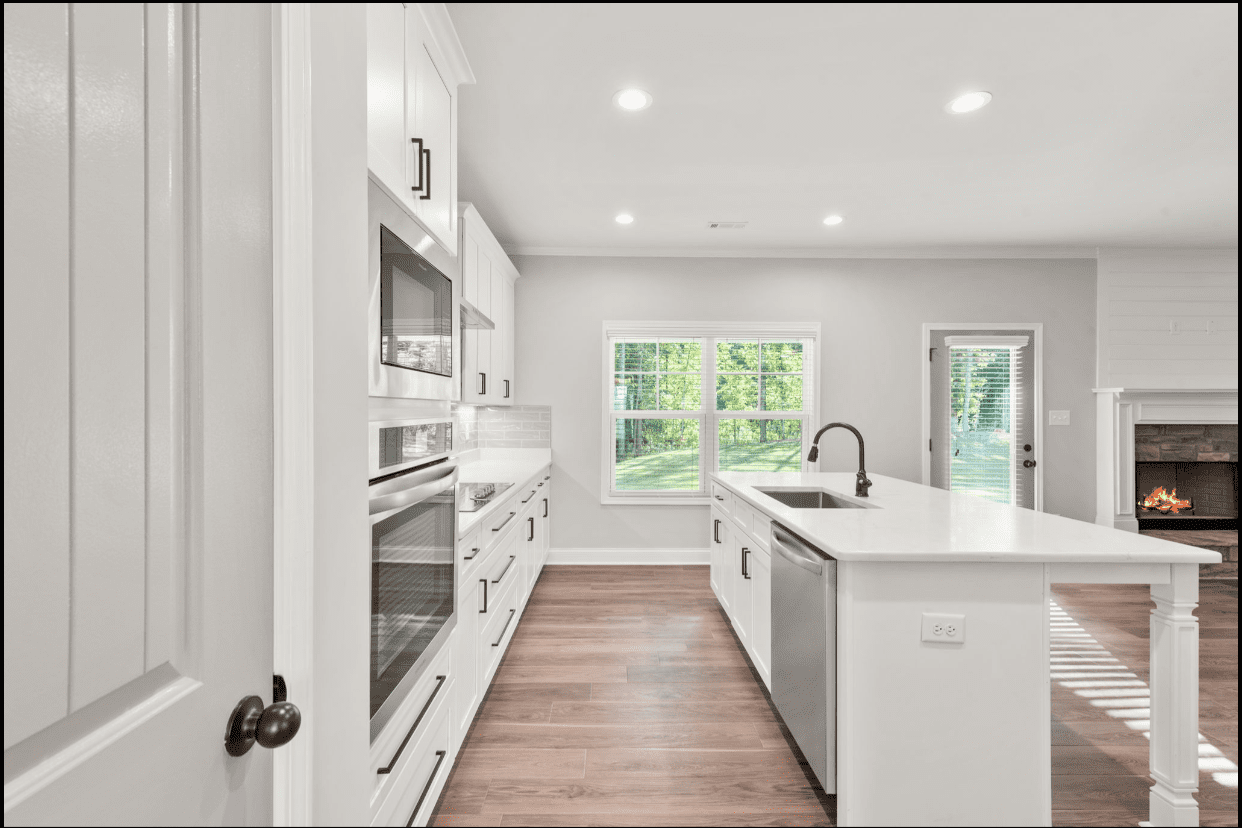 Modern white kitchen with island and wood floors.