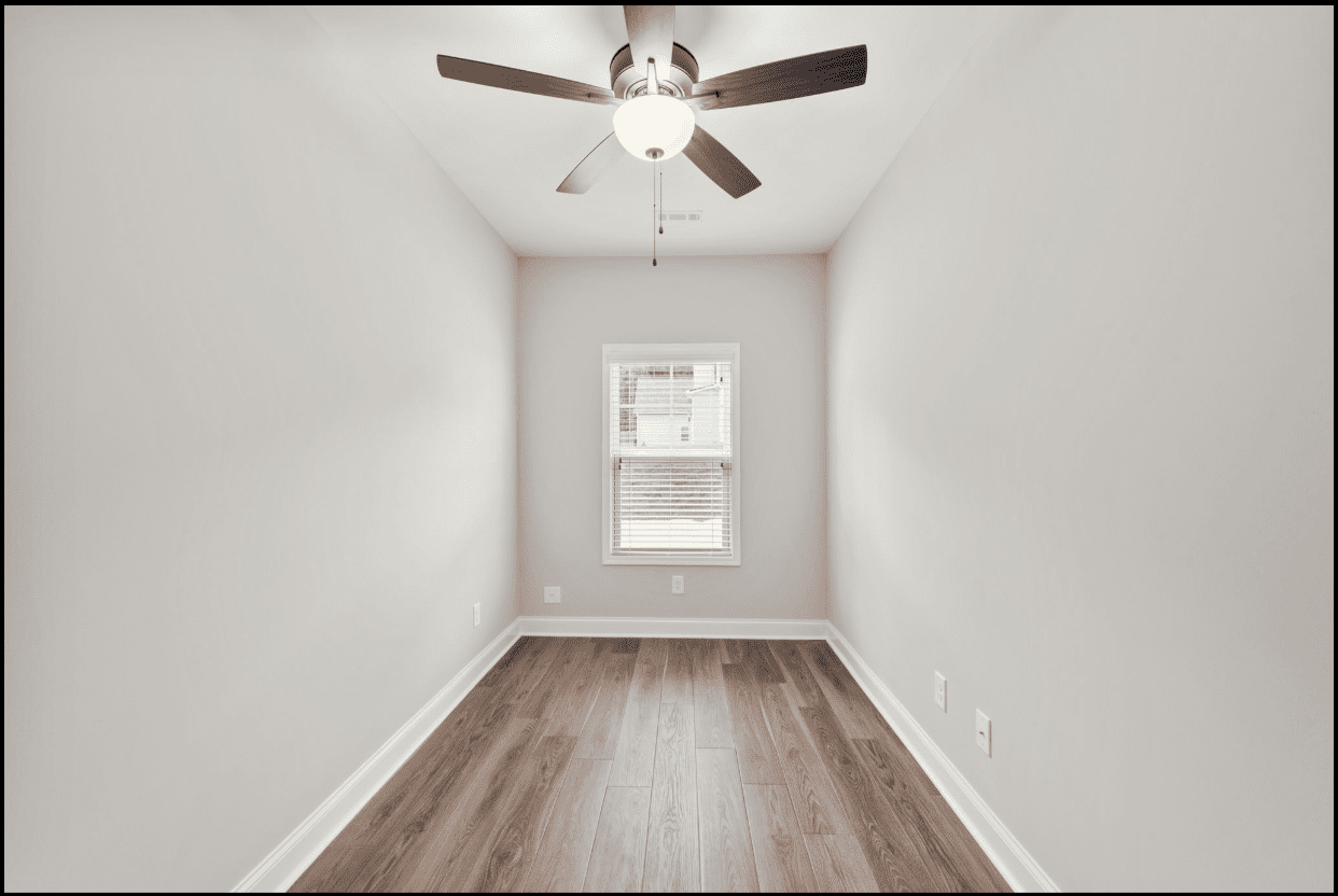 Empty room with ceiling fan and wood floor.