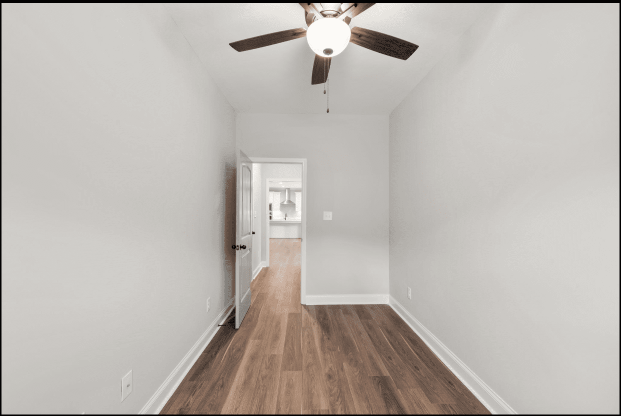 Empty room with hardwood floors and ceiling fan.