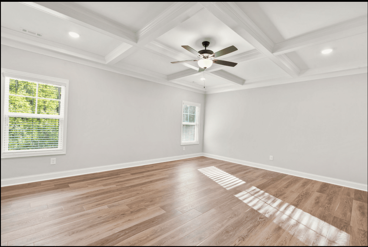 Empty room with hardwood floors and coffered ceiling.