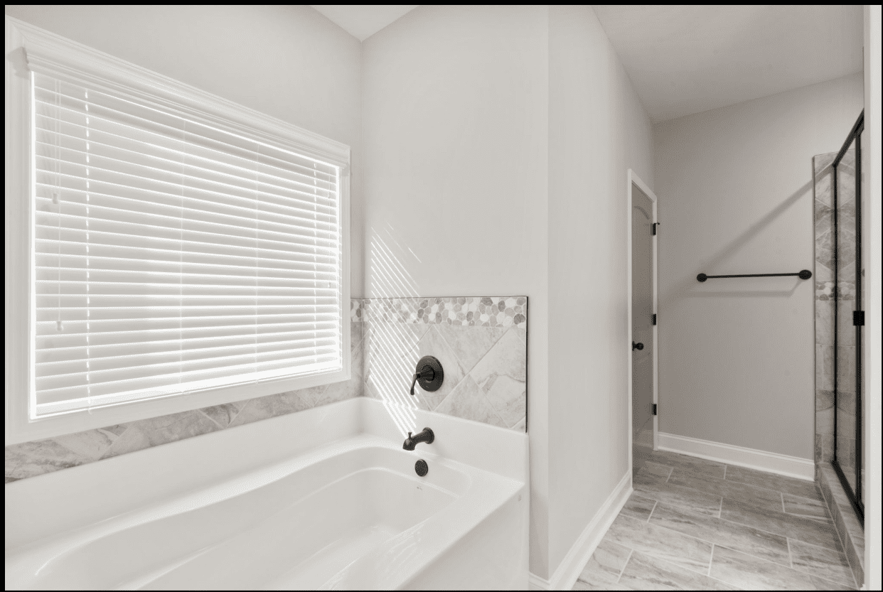 Modern bathroom with white tub and blinds.