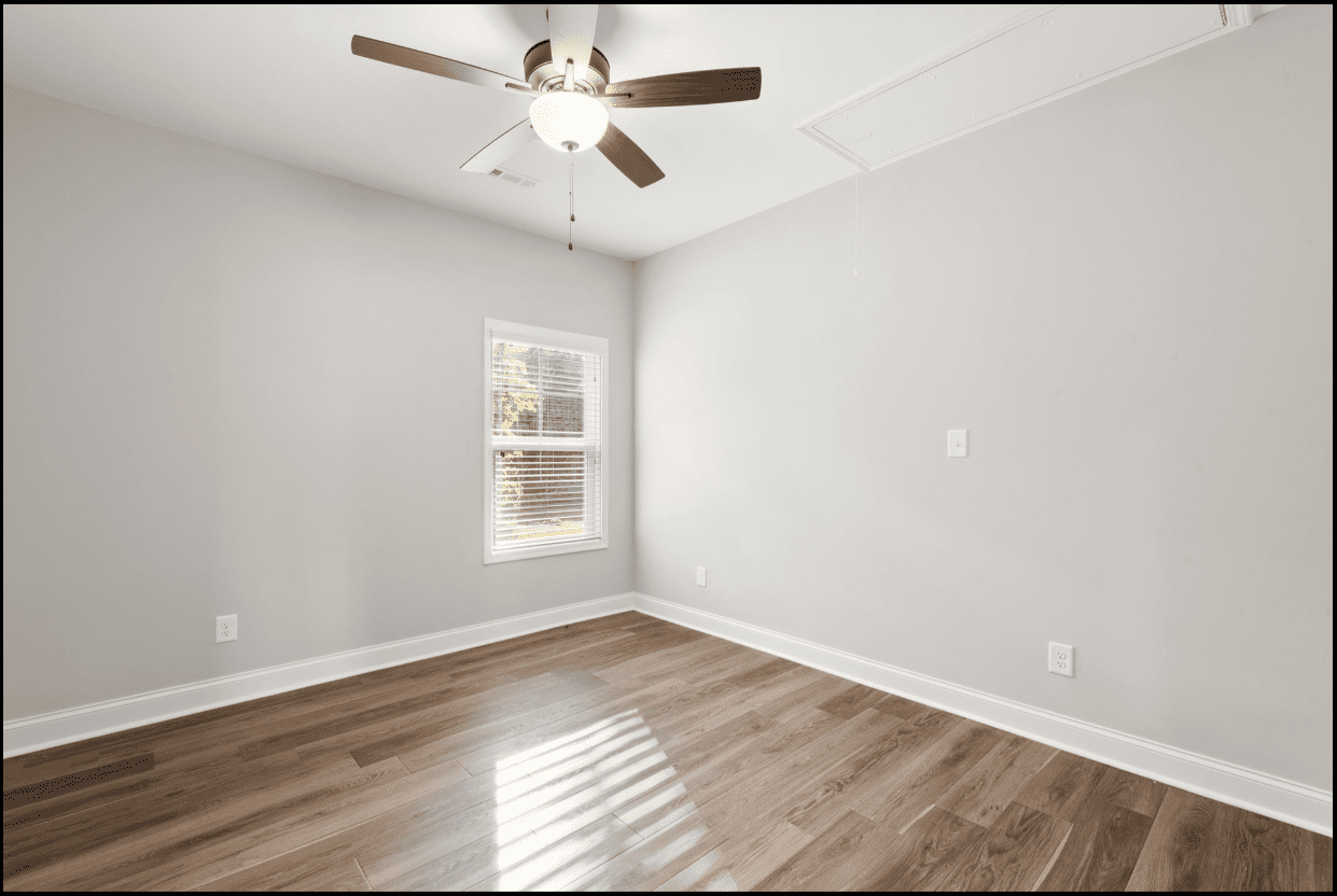 Empty bedroom with hardwood floors and ceiling fan.