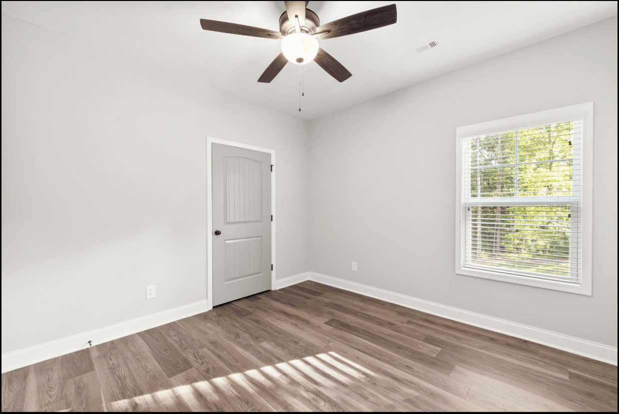 Empty bedroom with wood floor and window.