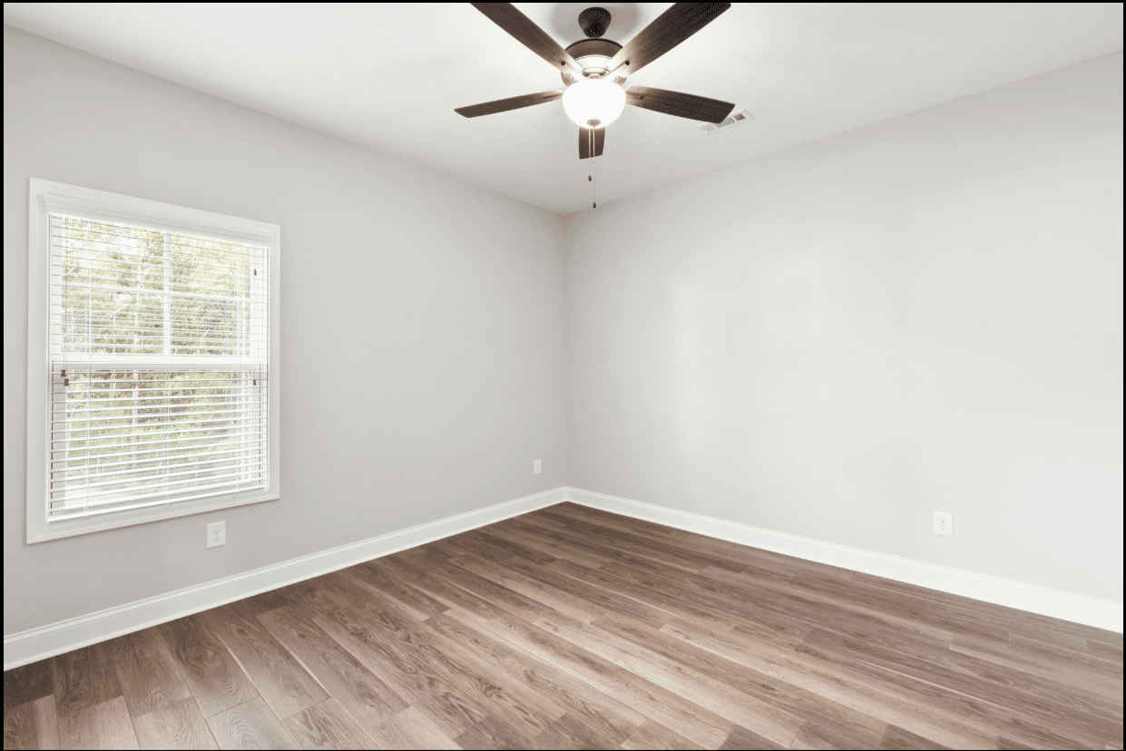 Empty bedroom with wood floor and ceiling fan.