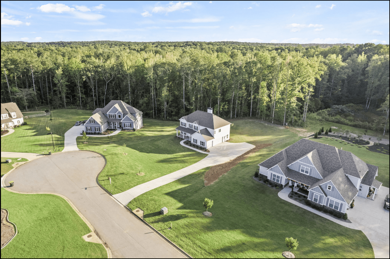 Aerial view of three houses in a wooded area.