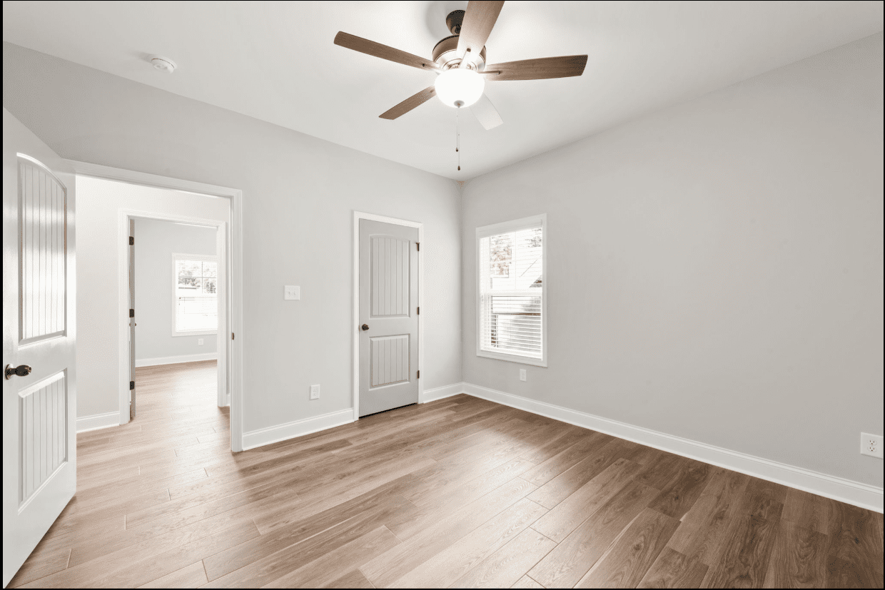 Empty bedroom with hardwood floors and ceiling fan.