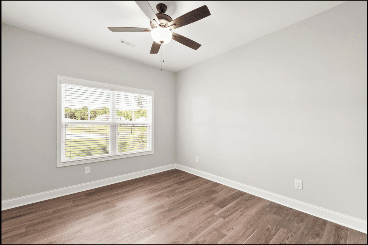 Empty bedroom with window and ceiling fan.