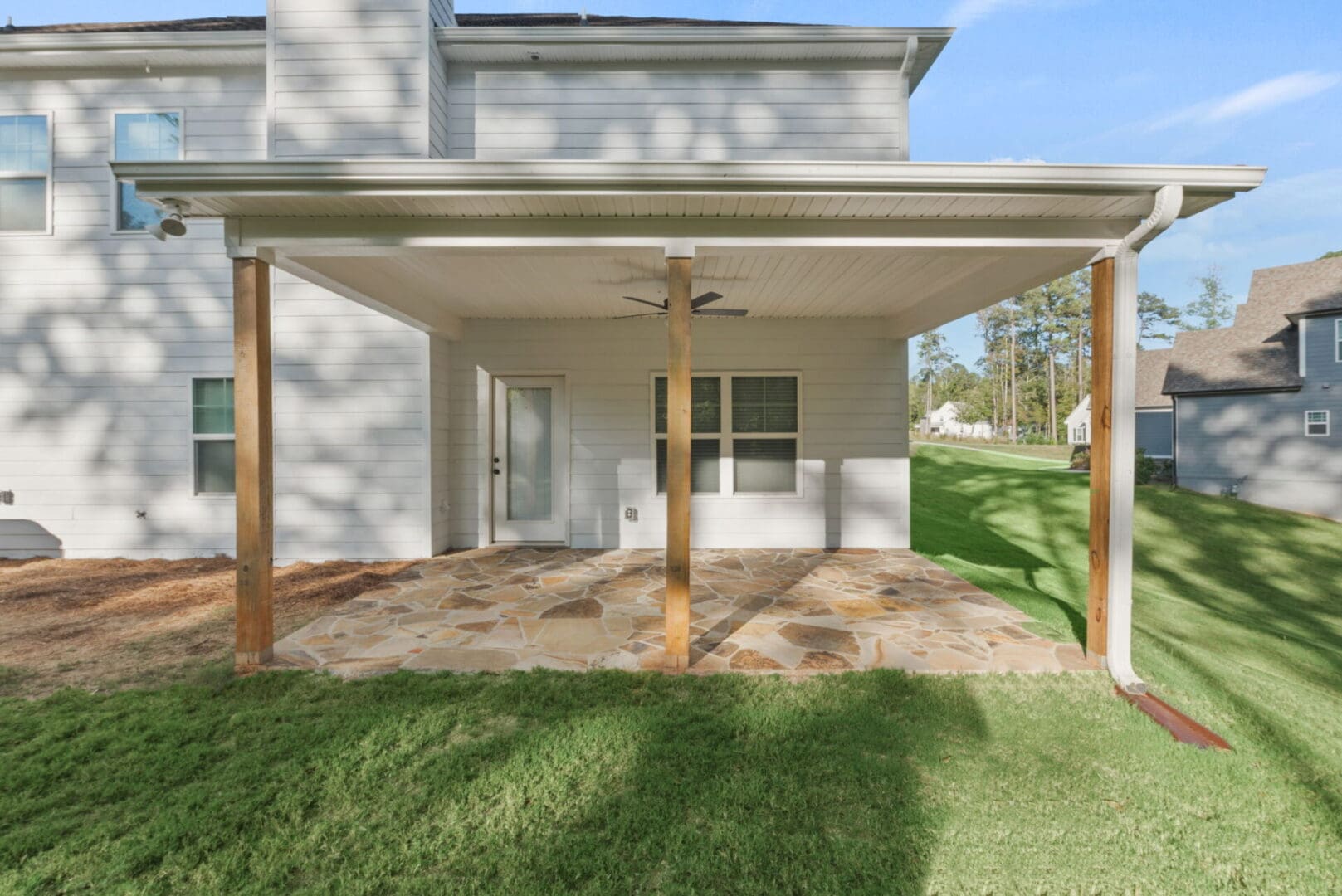 House patio with stone flooring and ceiling fan.