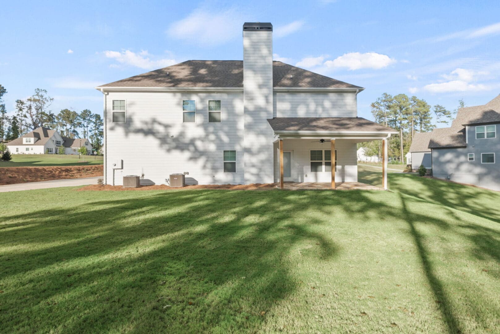White house with covered patio and lawn.